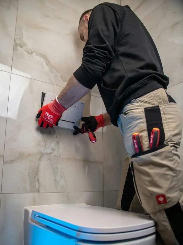 Monteur met rode werkhandschoenen aan het werk aan een betegelde wand